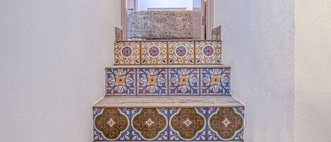 Una escalera con baldosas de madera ricamente decoradas y de colores, que lleva a una puerta de madera.