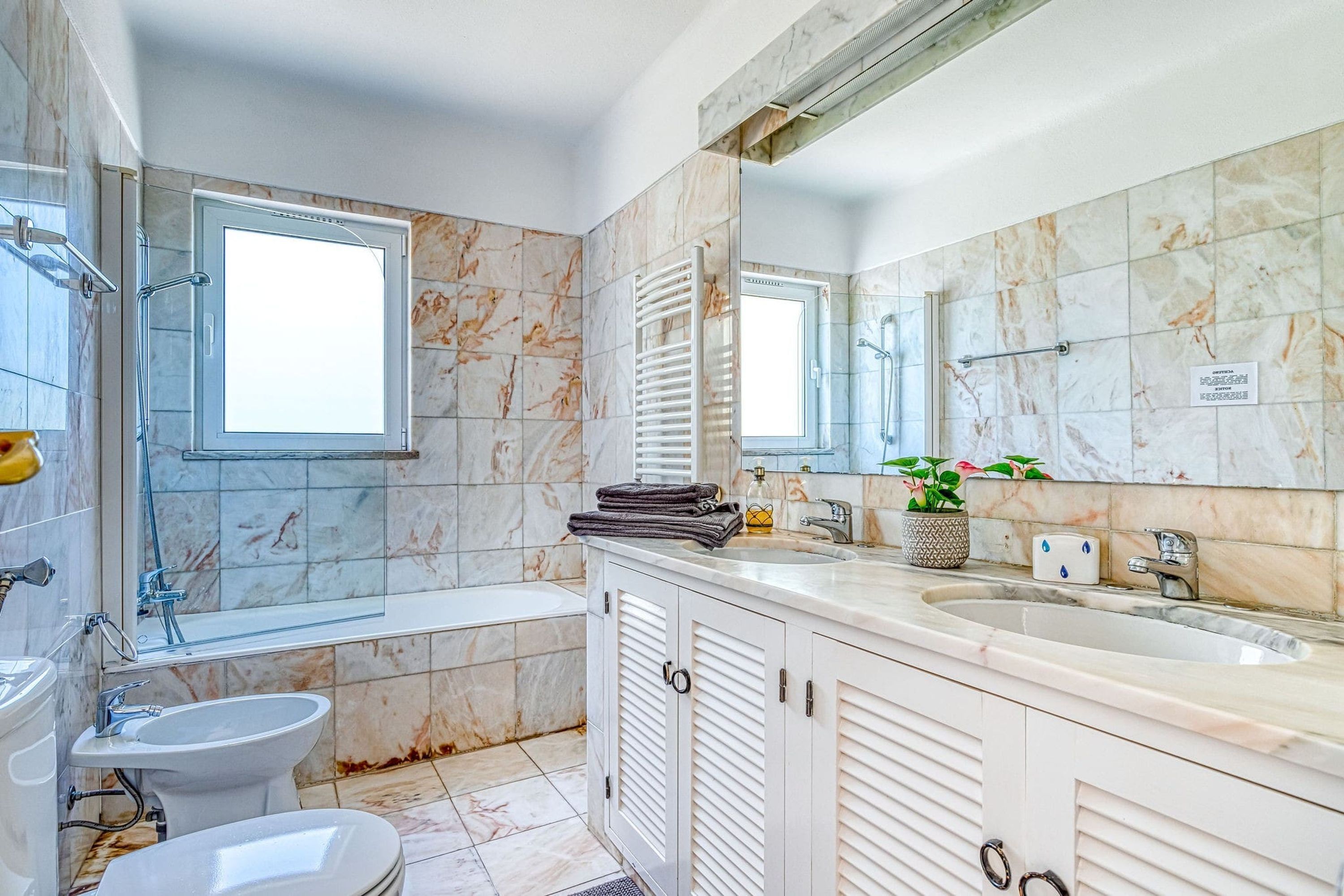 A modern bathroom with a bathtub, a sink, a bidet, and a toilet.