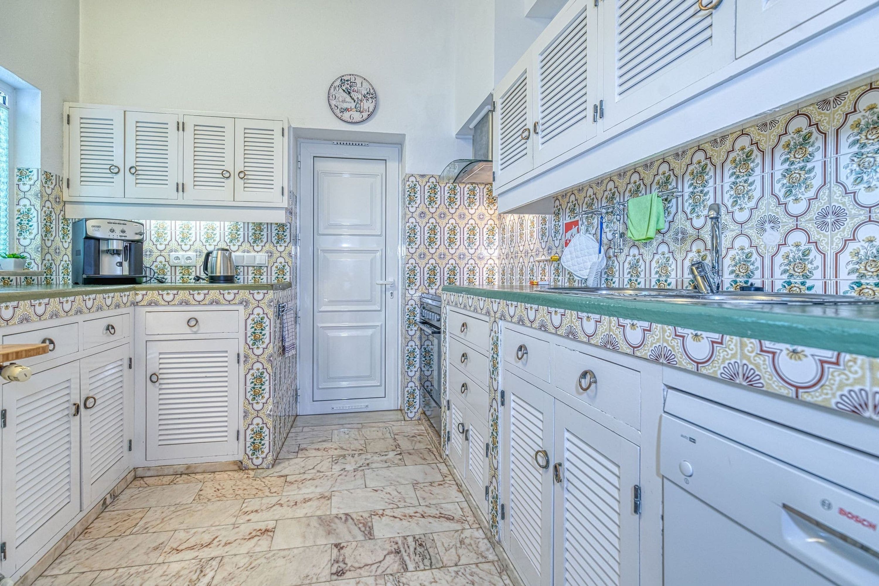 A kitchen with white cabinets, a coffee machine, and a Bosch dishwasher.