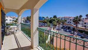 A balcony with a view of a residential area, featuring a tiled floor and a green railing.