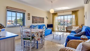 A living room with a dining table, blue sofa, and a TV.