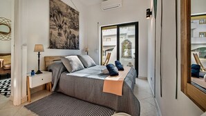 A bedroom with a bed, bedside tables, a large window, and a view of the outside. - 212 Aurora sol Casinha DO SOL (Lagoa)