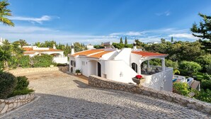 A white building with a red-tiled roof, a stone pathway, and surrounding greenery. - Toupeira Wonderful Well Furnished Villa (Lagoa)