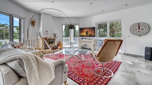 A spacious living room with a glass coffee table, comfortable seating, a fireplace, and large windows offering a view of the outdoors. - Toupeira Wonderful Well Furnished Villa (Lagoa)