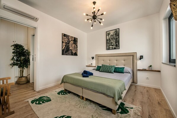 Un dormitorio con cama, candelabro, planta y obras de arte en las paredes.