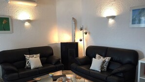 Una sala de estar con dos sofás de cuero negro, una mesa de centro de vidrio y una chimenea.