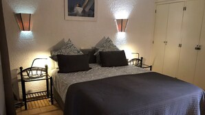 Un dormitorio con cama, dos mesitas de noche, un armario y dos luces empotradas.