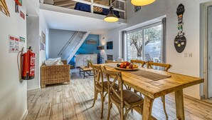 Een eetgedeelte met een houten tafel en stoelen, een vide erboven en uitzicht op de omgeving.