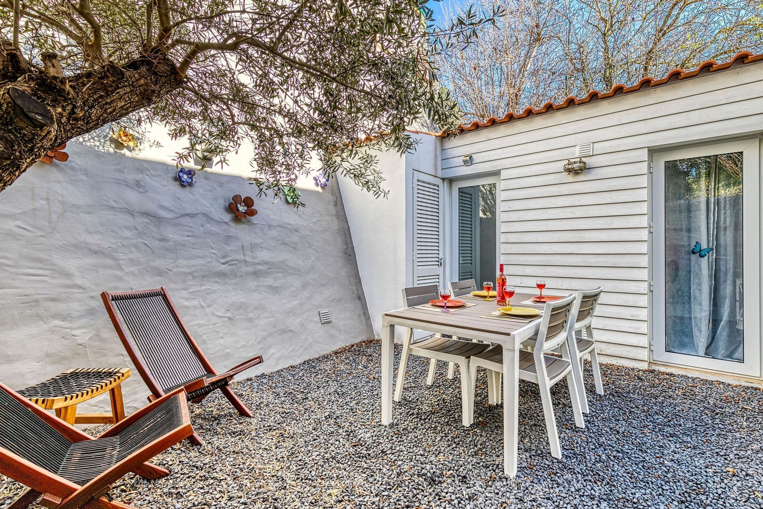 A patio with a table and chairs, a small chair, and a wall with decorative elements.