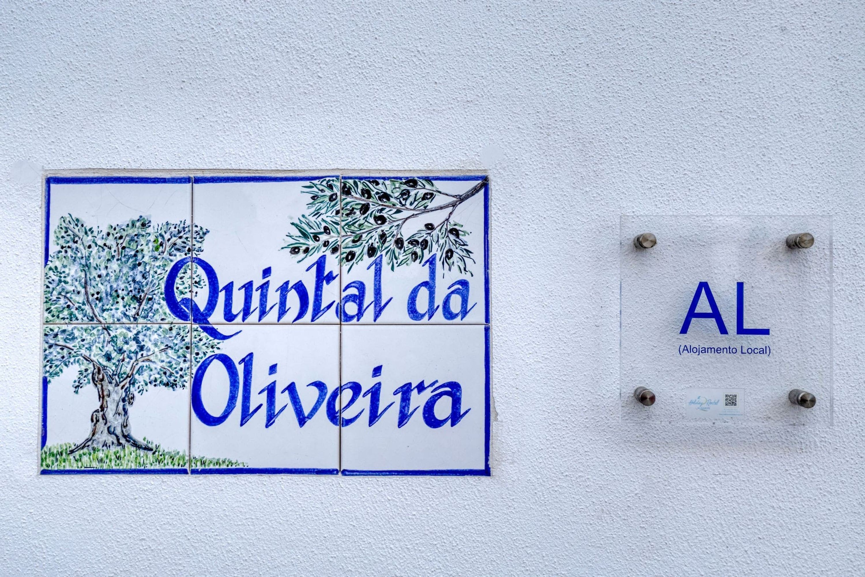 Une enseigne indiquant « Quintal da Oliveira » et « AL (Alojamento Local) », ce qui signifie qu’il s’agit d’un hébergement local.