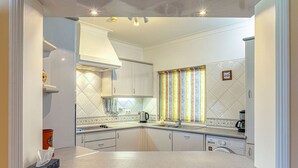 A modern kitchen with white cabinets, a stainless steel sink, and a striped curtain. - 61B Gramacho Apartment IN THE Heart OF Gramacho (Lagoa)