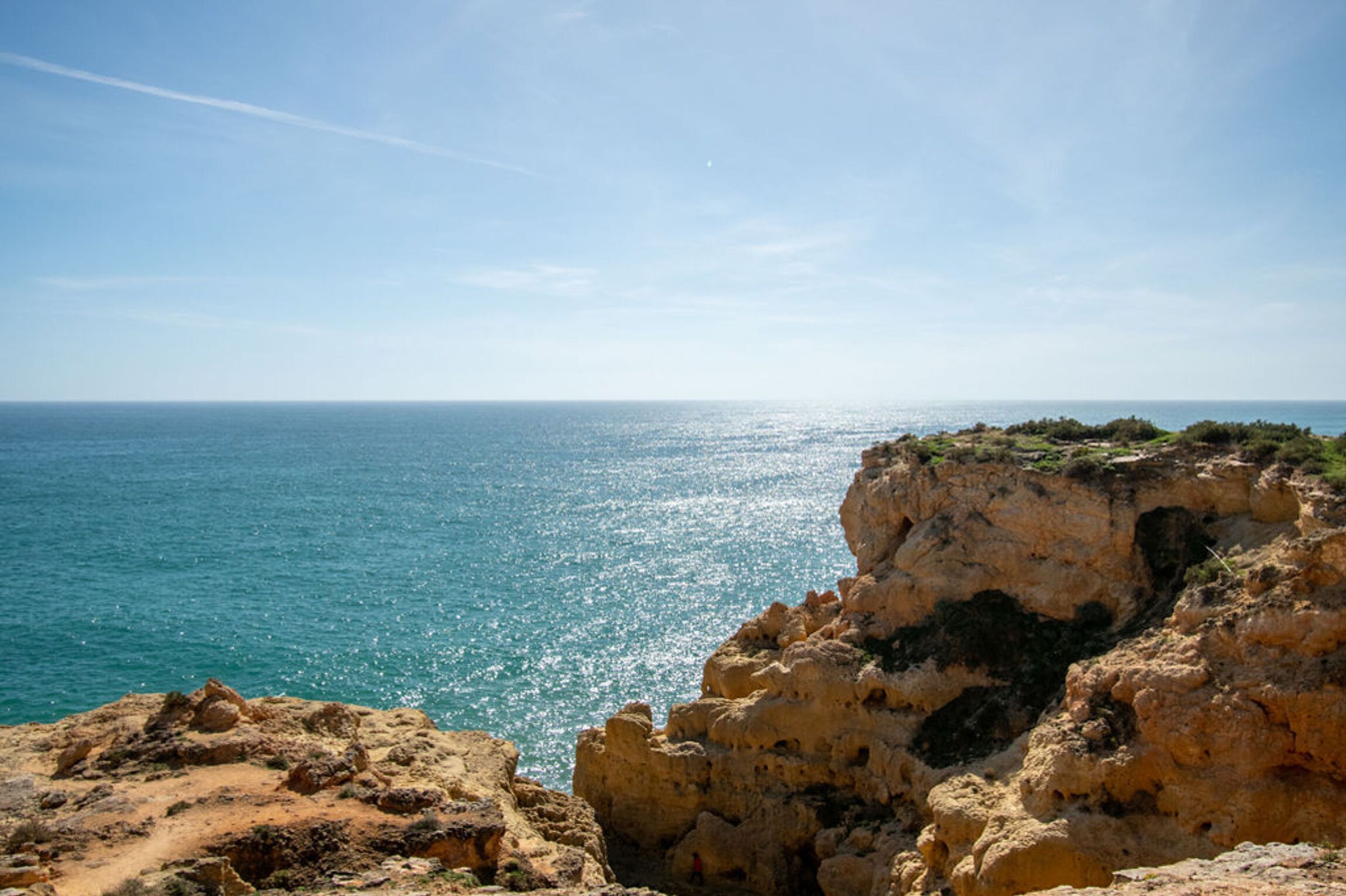 A coastal landscape with rocky cliffs and a clear view of the sea.