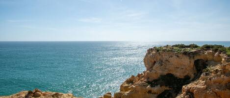 A coastal landscape with rocky cliffs and a clear view of the sea.