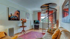 A living room with a sofa, a TV, a radiator, a painting, and a staircase. - Outra Vez Spacious Apartment 5 Minute Walk From (Lagoa)