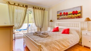 A bedroom with a bed, two bedside tables, a painting, and a view of the outdoors. - Outra Vez Spacious Apartment 5 Minute Walk From (Lagoa)