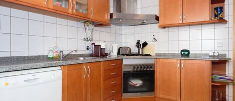 A kitchen with wooden cabinets, a dishwasher, an oven, and a stainless steel range hood.