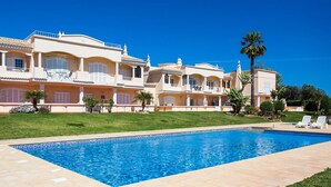 A hotel with a swimming pool, multiple balconies, and lush greenery. - 11 Marinha Two Bedroom Apt at Praia do Marinha (Lagoa)