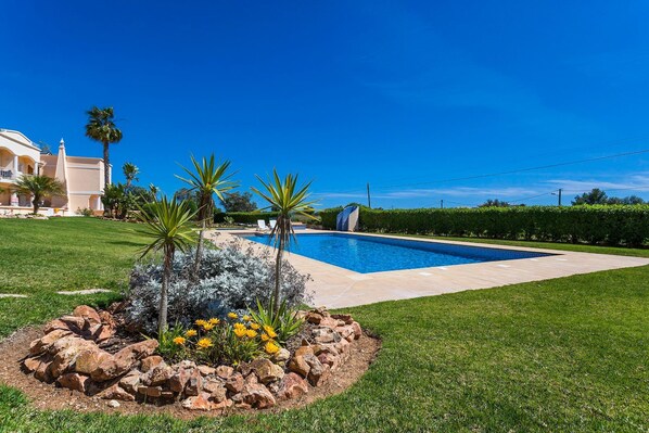 A swimming pool surrounded by a landscaped garden with rocks and plants.