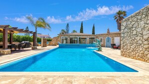 Una piscina con paredes de piedra y una pérgola.