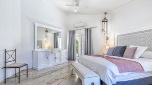 Un dormitorio con una cama grande, un banco, una silla, un armario y un ventilador de techo.