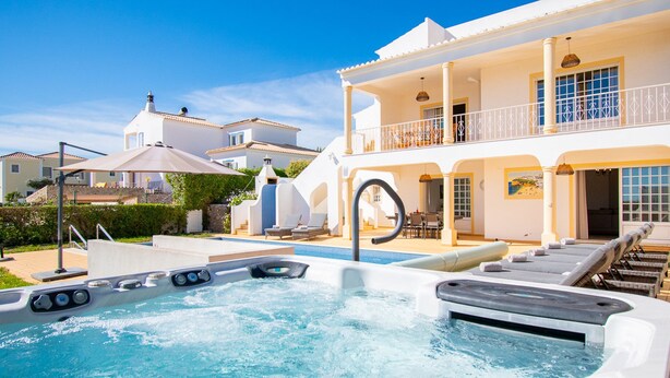A luxurious pool area with multiple hot tubs, lounge chairs, and a spacious outdoor deck. - Casa Filipa Lower Floor (Lagoa)