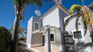 A modern two-story house with a covered patio, satellite dish, and air conditioning units. - Albatroz Gorgeous Spacious Villa IN Carvoeiro (Lagoa)