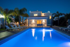 A modern house with a swimming pool, lounge chairs, and a well-lit patio area. - Albatroz Gorgeous Spacious Villa IN Carvoeiro (Lagoa)