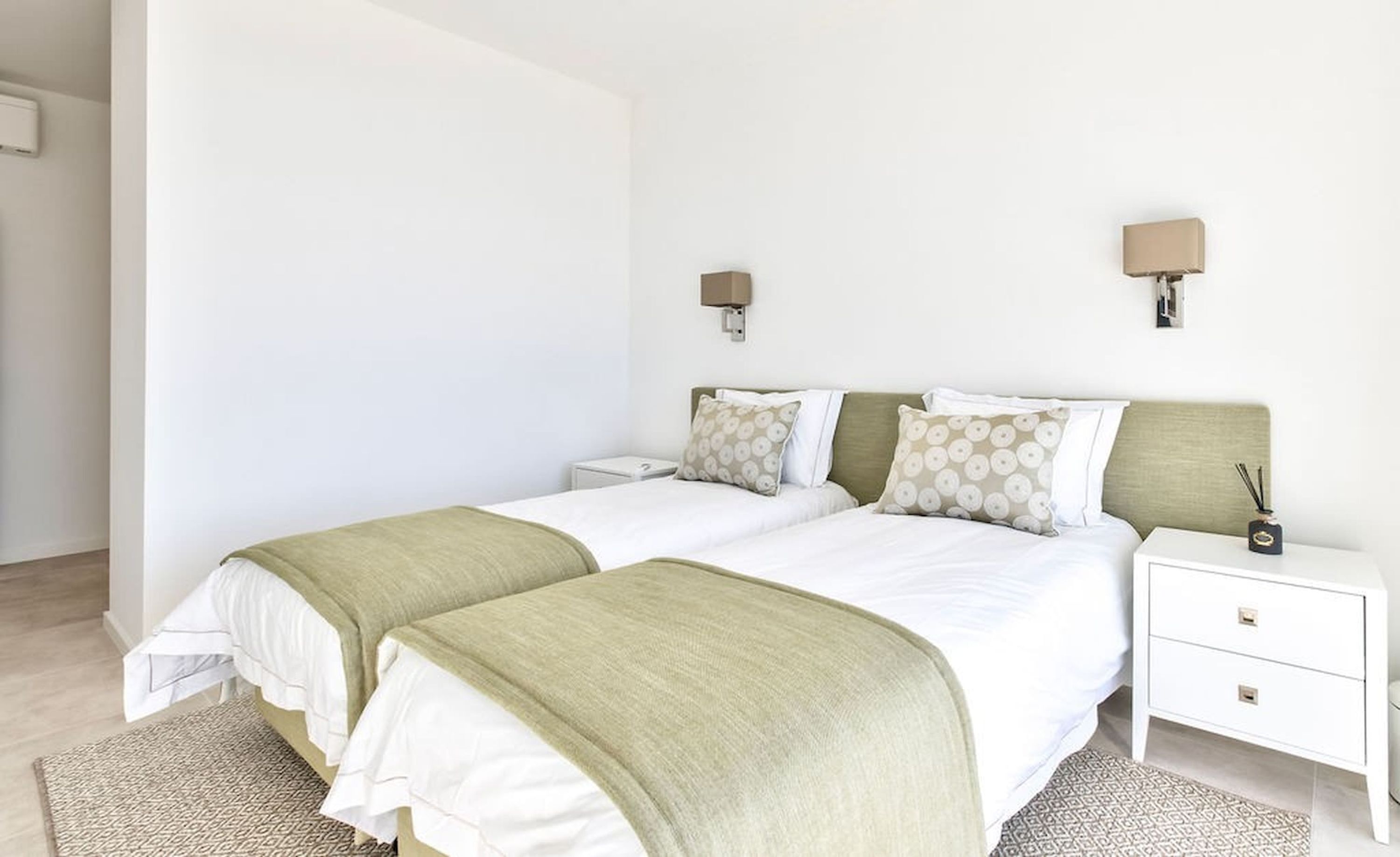 Una cama doble con dos almohadas, una mesita de noche con lámpara y una pequeña mesa con un objeto decorativo.
