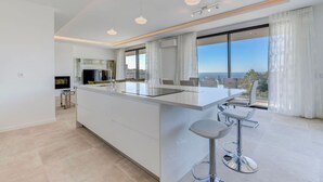 Una cocina moderna con una isla grande, taburetes de bar y vista al mar.