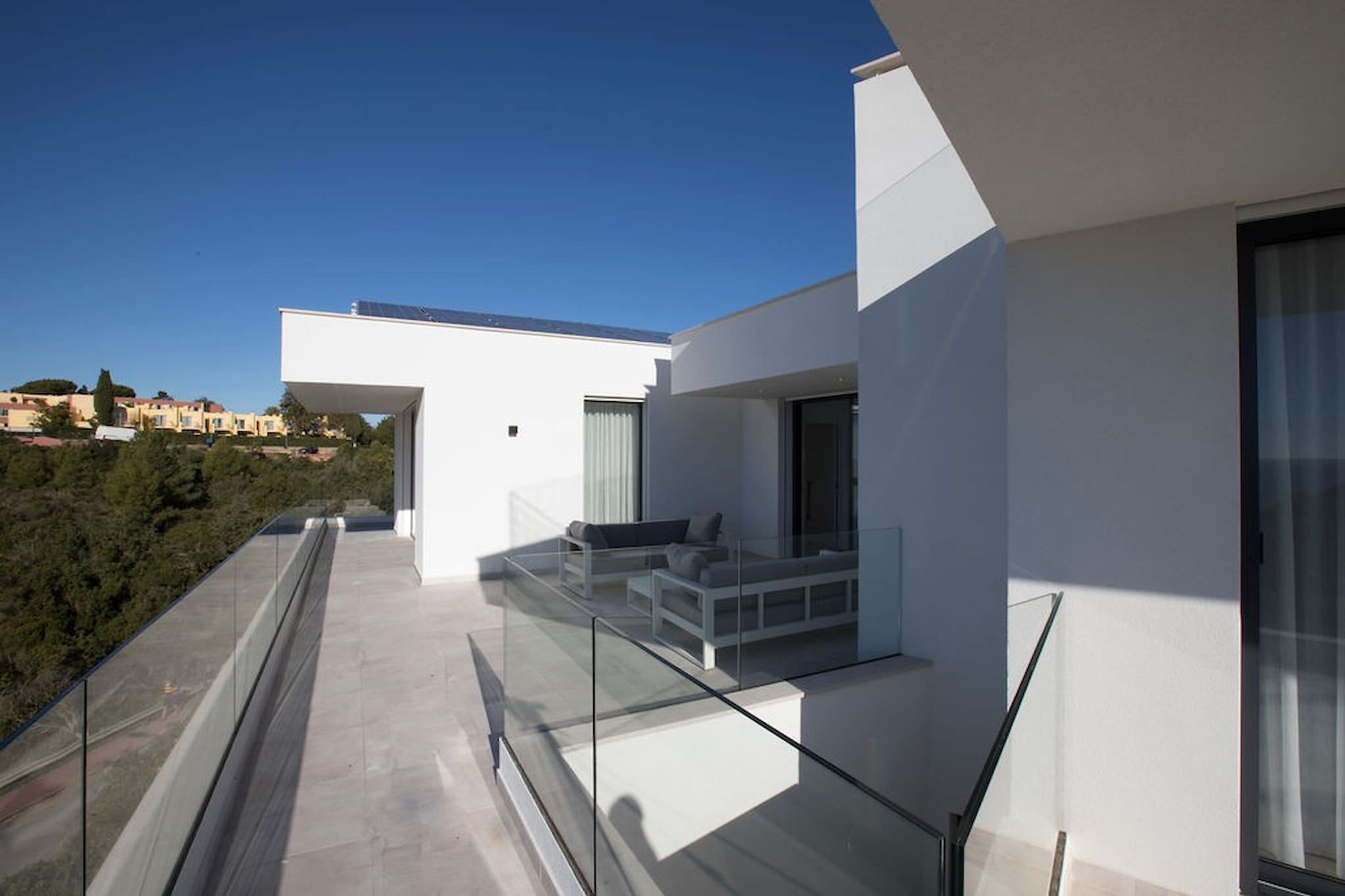 Un balcon moderne avec des garde-corps en verre donnant sur un quartier résidentiel.