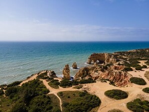 A coastal landscape with rocky formations, a sandy beach, and a clear view of the ocean. - 10 Marinha Two Bed Apt At Award Wining Beach (Lagoa)