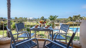 A terrace with a table set for two, overlooking a swimming pool and a lush garden. - 10 Marinha Two Bed Apt At Award Wining Beach (Lagoa)