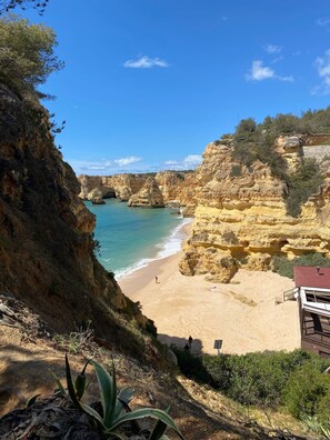 A coastal landscape with cliffs, a beach, and a building with a red roof. - 10 Marinha Two Bed Apt At Award Wining Beach (Lagoa)