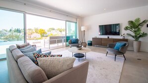 A modern living room with a sofa, armchairs, a coffee table, and a TV. - Casa da Lua in Carvoeiro (Lagoa)