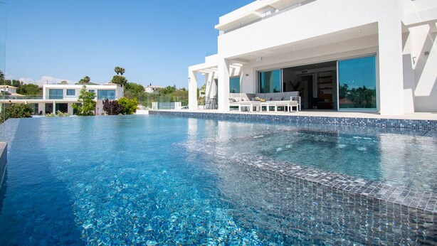 A modern hotel with a large swimming pool, outdoor seating area, and a view of the surrounding landscape. - Casa da Lua in Carvoeiro (Lagoa)