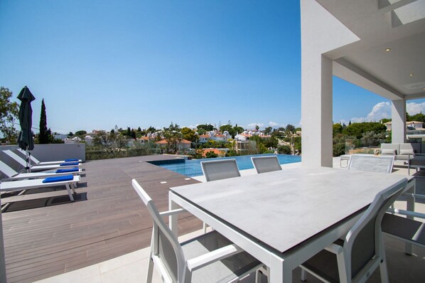 A rooftop pool area with lounge chairs and a dining table, overlooking a residential area. - Casa da Lua in Carvoeiro (Lagoa)
