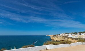 A coastal town with white buildings, a clear blue sky, and a boat on the sea. - Vida DE Praia Vida DE Praia (Lagoa)