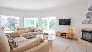 A modern living room with a beige sofa, a coffee table, and a fireplace. - La Pausa in Carvoeiro (Lagoa)