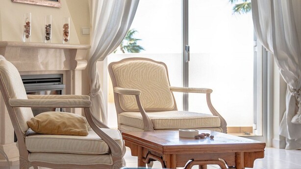 A living room with two armchairs, a coffee table, and a fireplace. There is a large window with curtains, and a painting on the wall. - 54 Golf mar Carvoeiro Apartment With Fabul (Lagoa)