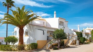 A white building with a yellow base, a palm tree, and a clear blue sky. - 54 Golf mar Carvoeiro Apartment With Fabul (Lagoa)