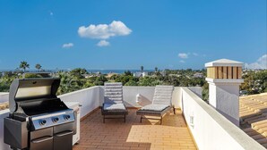A rooftop terrace with a grill, two cushioned chairs, and a view of the sea. - 99b Aldeia Golfmar Superb 2-bedroom Apartment (Lagoa)