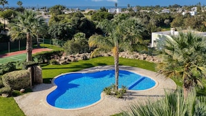A swimming pool surrounded by greenery, with a view of houses and a clear sky. - 99b Aldeia Golfmar Superb 2-bedroom Apartment (Lagoa)