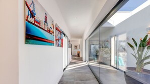 A modern hallway with large windows, a glass wall, and a potted plant. - Casa Blanca Magnificent 4 Bedroom Villa With MOD (Lagoa)