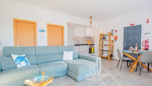 Un saló modern amb un sofà blau clar, una taula de centre de vidre i una zona de menjador amb taula i cadires de fusta.