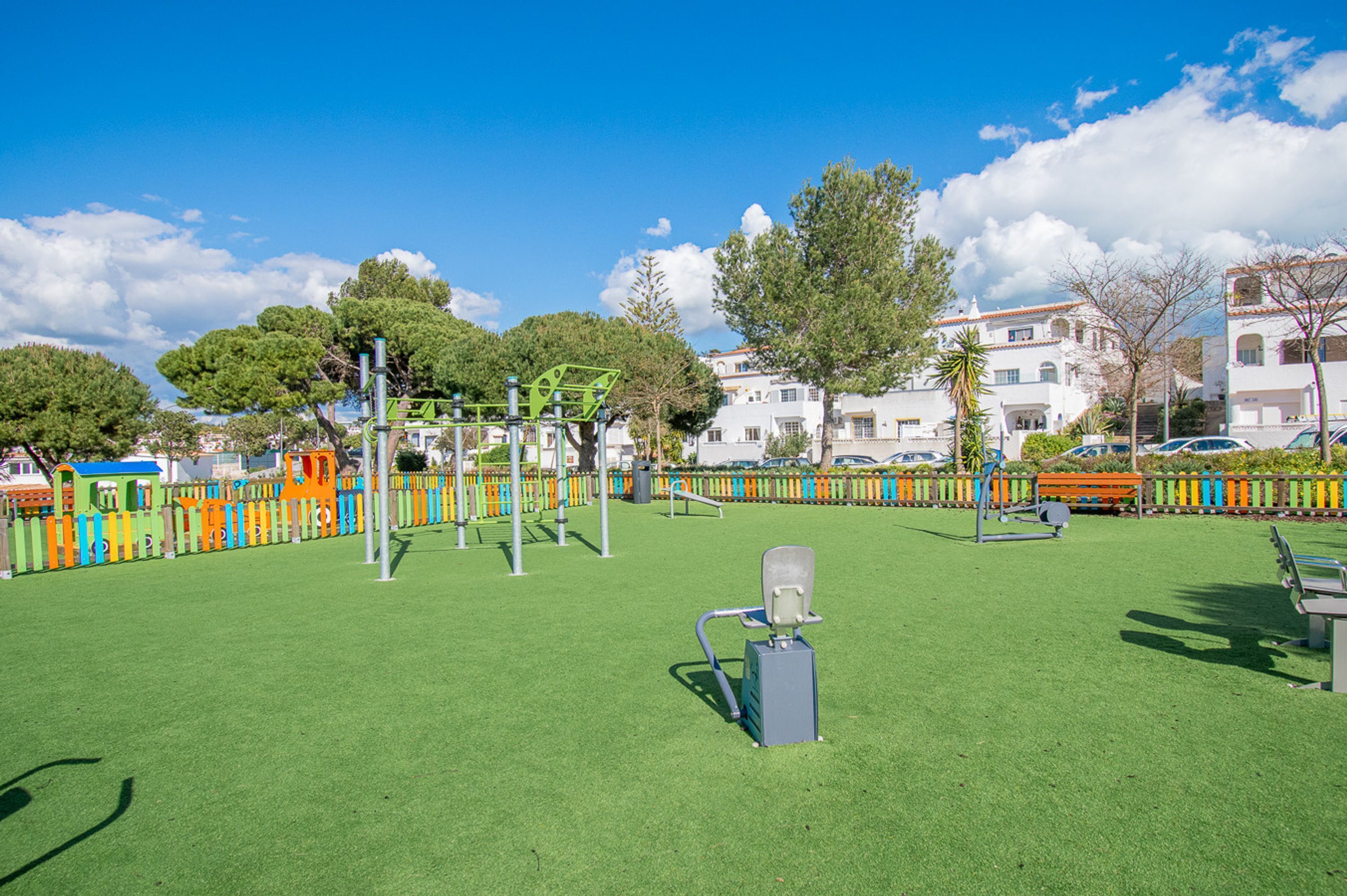 A playground with exercise equipment, a bench, and a fence.