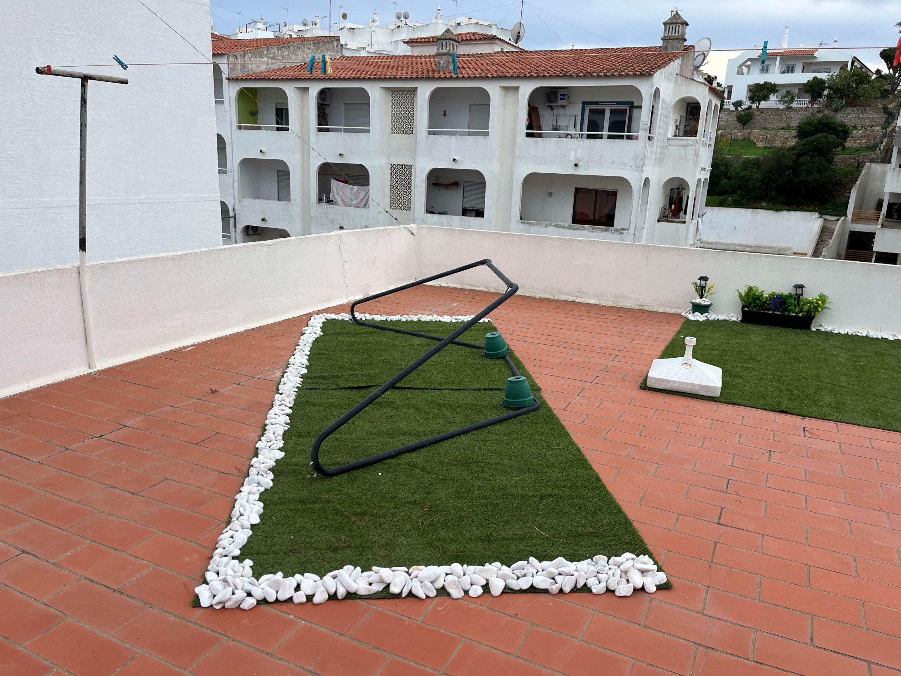 A rooftop with artificial grass, a metal structure, and a white statue.