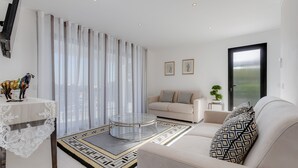 A modern living room with a round glass coffee table, a sofa, a lace table, and a patterned rug. - 125 Quinta do Paraiso - Casa Jacqueline (Lagoa)