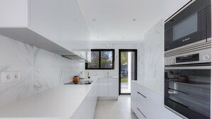 A modern kitchen with white cabinetry, a Bosch oven, and a large window providing natural light. - 125 Quinta do Paraiso - Casa Jacqueline (Lagoa)