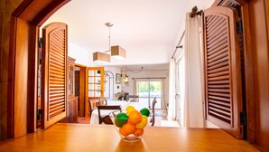 Un comedor con una mesa y sillas de madera, un cuenco de fruta, y vistas a una cocina y comedor.