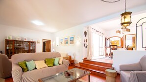 Una sala de estar con un sofá color beige, una mesa de centro de vidrio y un aparador de madera.